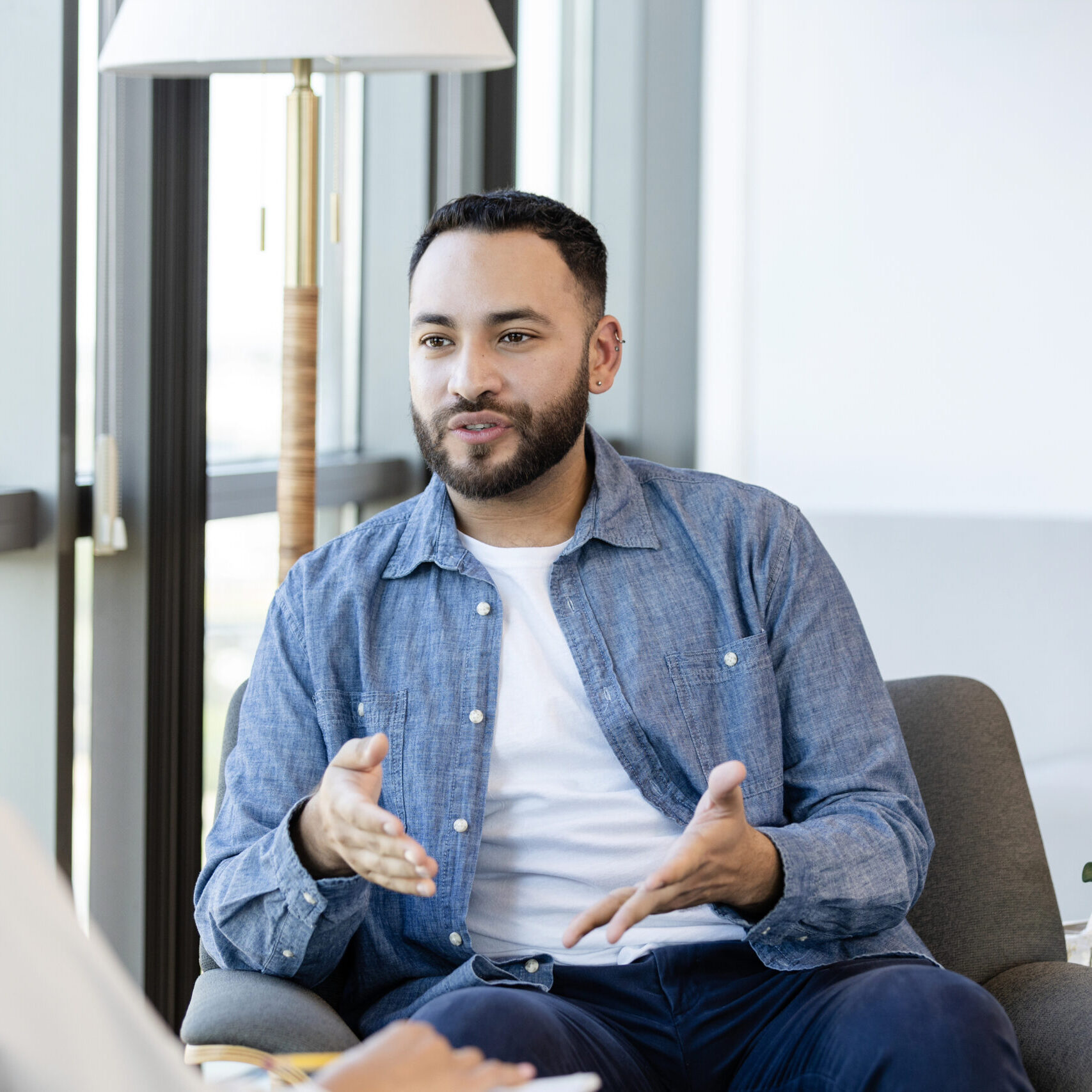 A young man gestures as he shares something during a therapy session.